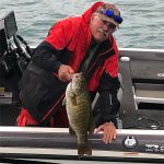 Man with smallmouth bass side of boat img2546